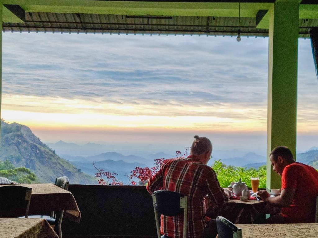 two people sitting at a table with a view of mountains at Hilltop Guest House in Ella