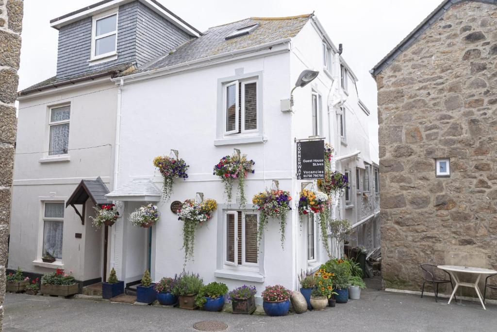 a white house with flowerpots in front of it at Cornerways Guest House in St Ives