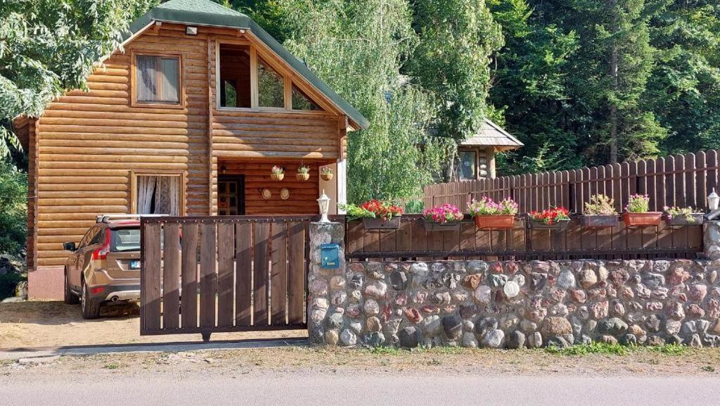 a wooden cabin with a fence and flowers on it at Lodge House Tara in Kolašin