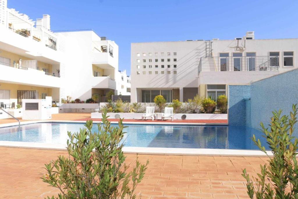 a swimming pool in front of some buildings at Apartamento Canada Formosa Cabanas Beach by Your Home Algarve in Cabanas de Tavira