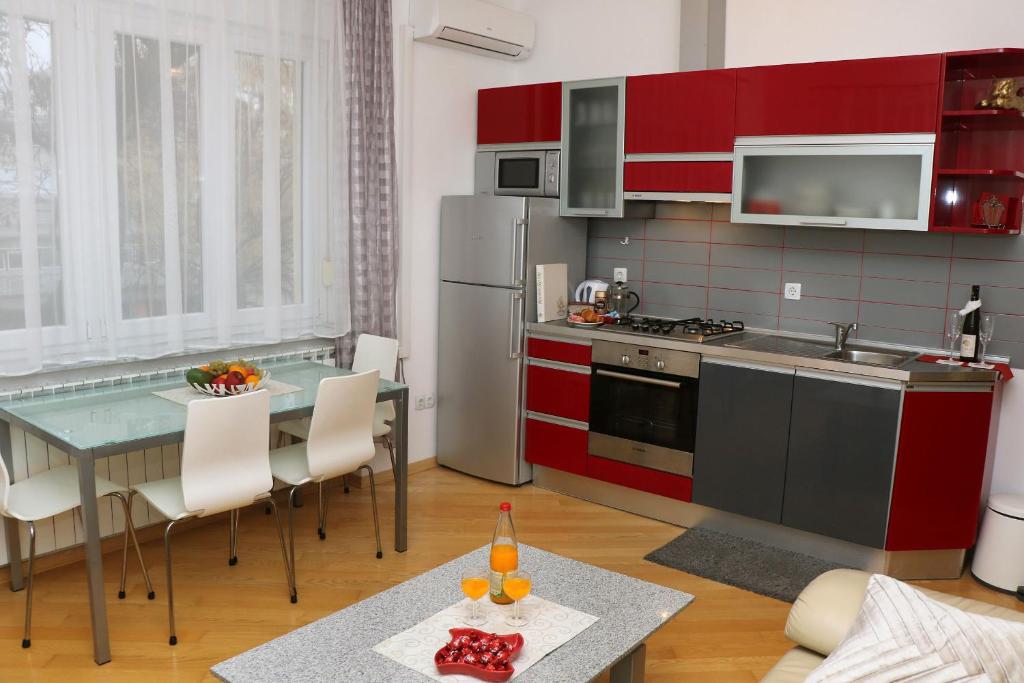 a kitchen with red cabinets and a table with chairs at Apartment Elena 1, Zagreb City with garage in Zagreb