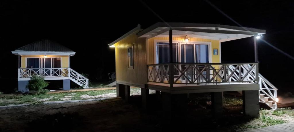 une petite maison jaune avec terrasse couverte la nuit dans l'établissement Harrys Cottage 4, à Dulcina