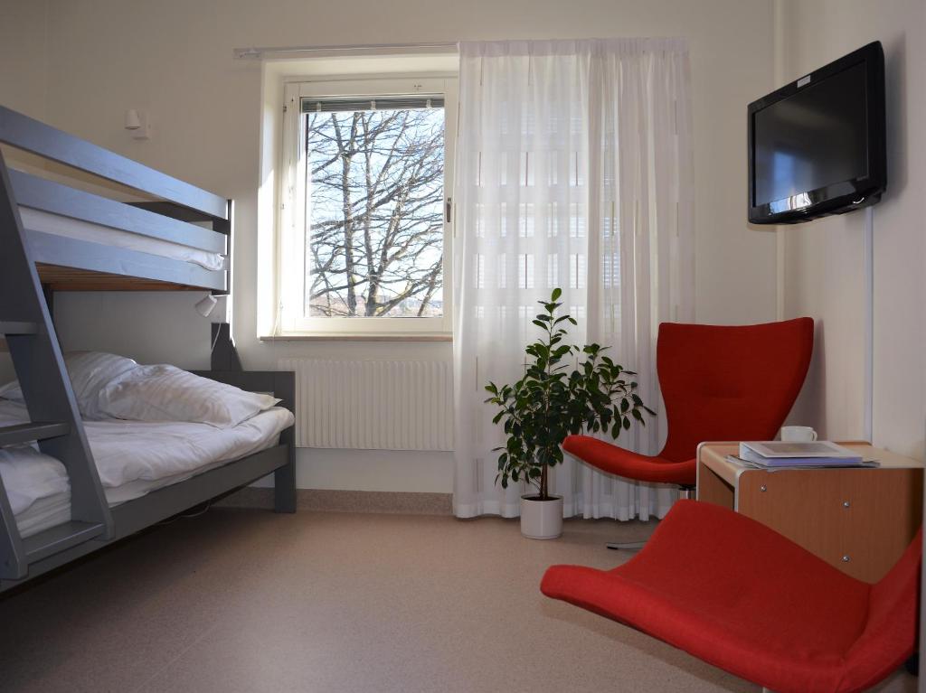 sypialnia z łóżkiem piętrowym i czerwonym krzesłem w obiekcie Katrinebergs Folkhögskola B&B w mieście Vessigebro