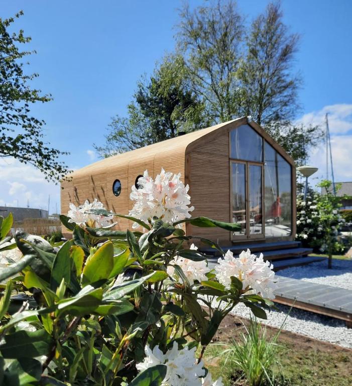 a tiny house in a garden with flowers at Wikkelhuis 12 in Stavoren