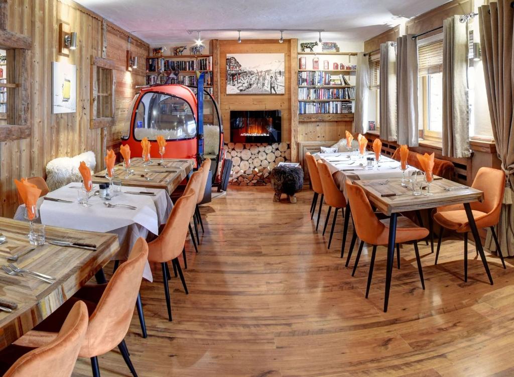 a restaurant with tables and chairs and a fireplace at Hôtel Les Cimes in Megève