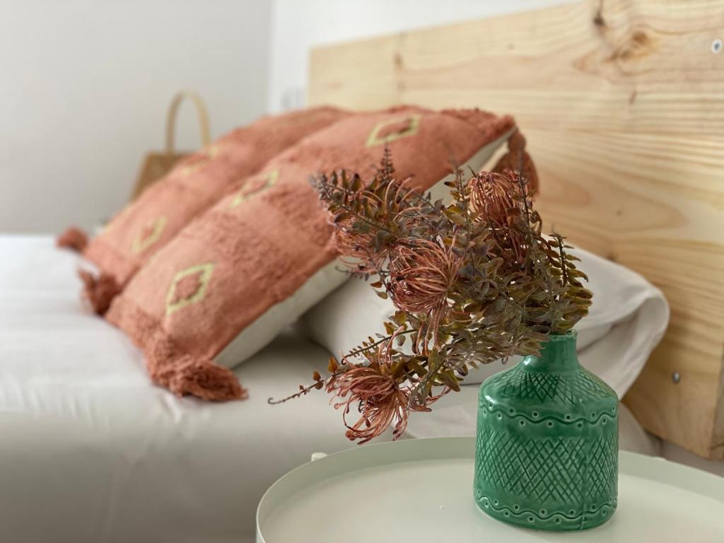 a green vase with flowers on a table next to pillows at Housingleon- Camino de Santiago by Bike I in León