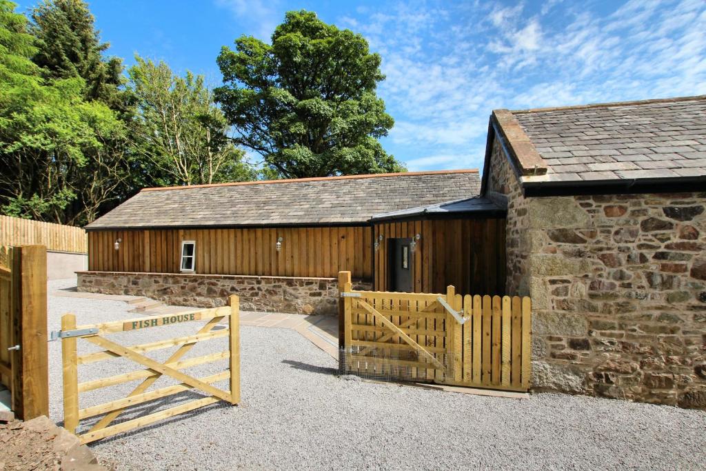 a barn with a wooden gate and a stone building at The Fish House in Kirkcudbright