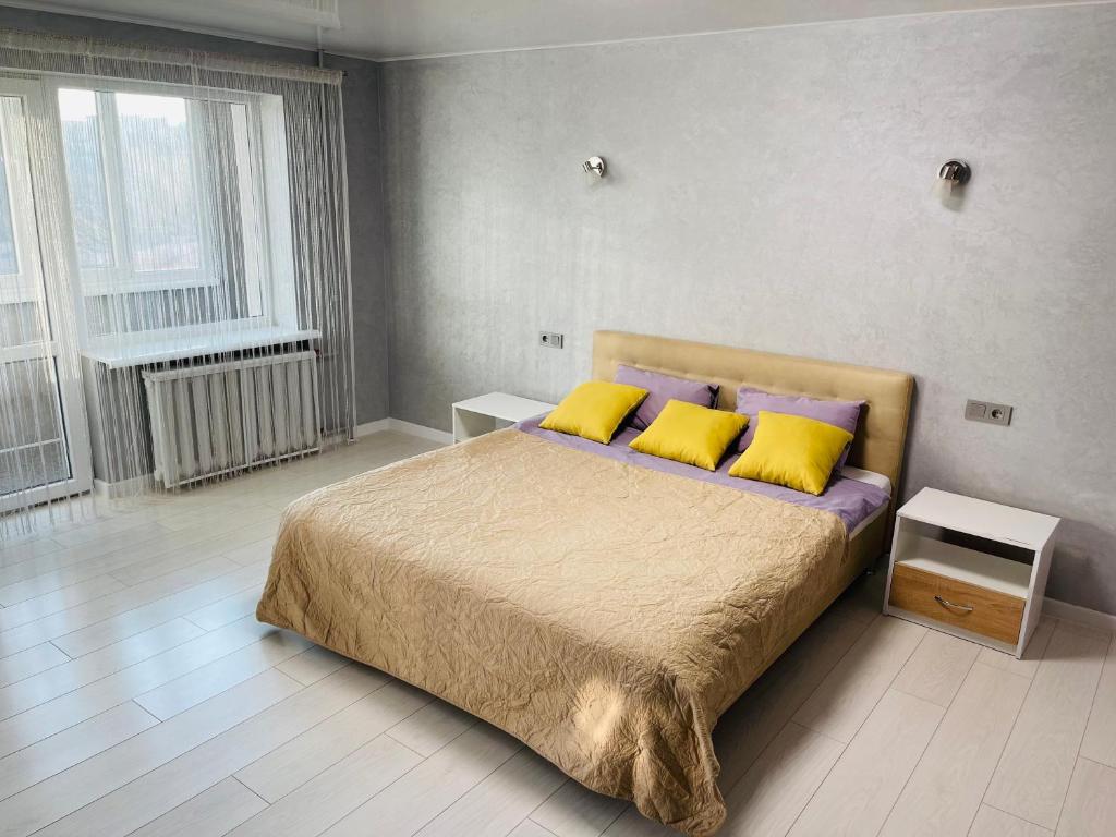 a bedroom with a bed with yellow and purple pillows at Апартаменты LUX в центре. Ярослава Мудрого 72 (97й квартал) in Kryvyi Rih