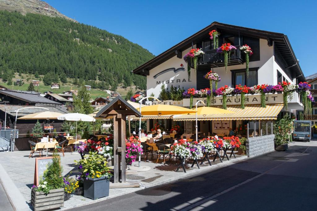 a building with tables and chairs and flowers in front of it at Hotel Mistral Superior in Saas-Fee