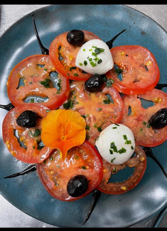 a plate of food with tomatoes and olives and sauce at Auberge du Savel in Clavans-en-Haut-Oisans