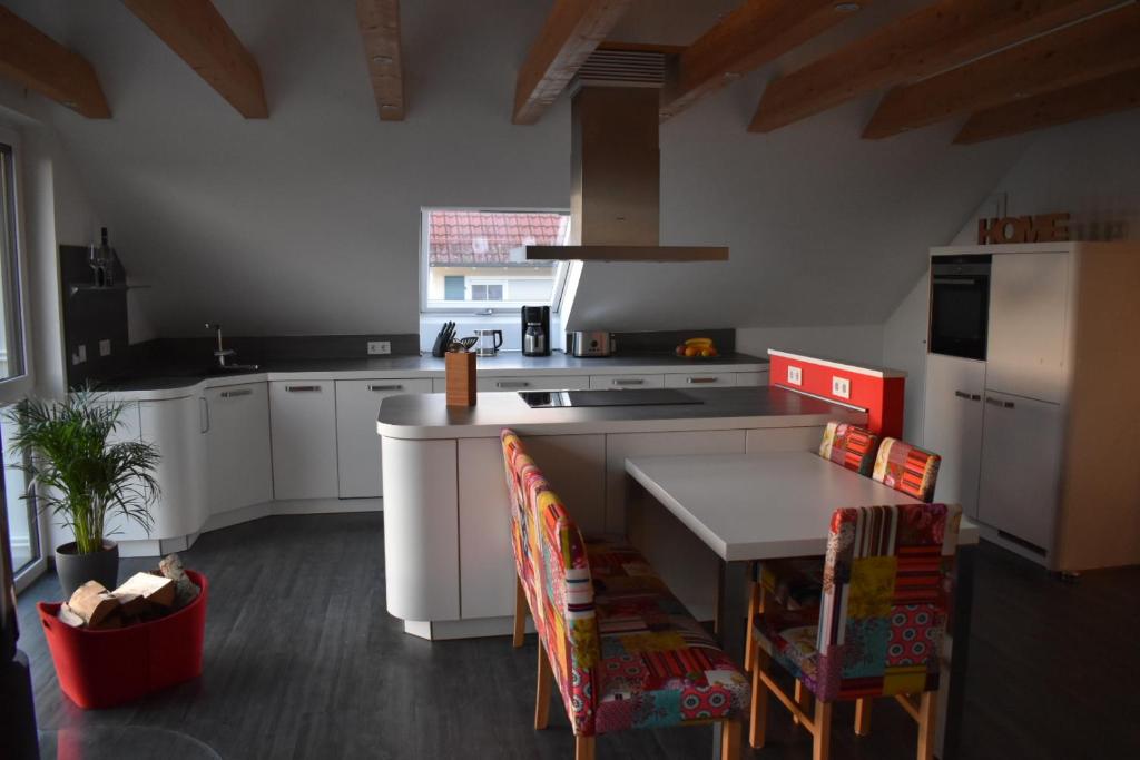 a kitchen with white cabinets and a table with chairs at Ferienwohnung 360° in Himmelkron