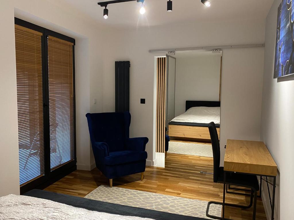 1 dormitorio con cama, silla azul y escritorio en Kamienica Nova 13 en Krosno