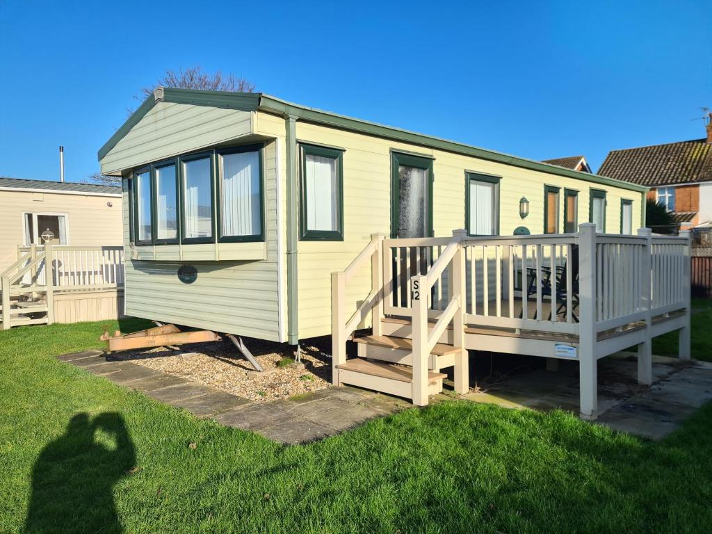 a green tiny house with a porch and a deck at 8 Berth Northshore (The Westmorland) in Lincolnshire