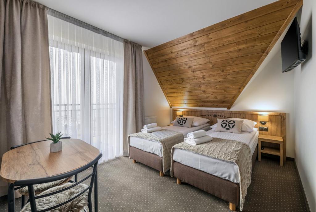 een hotelkamer met twee bedden en een tafel bij Janosówka in Czarna Góra