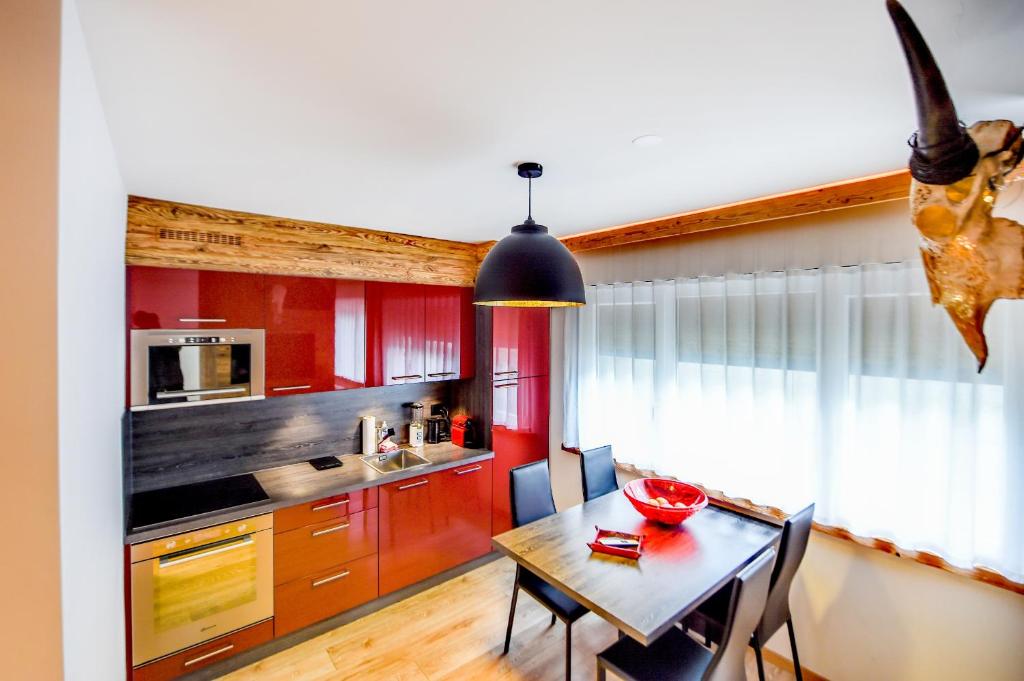 克萊恩 蒙塔納的住宿－Apartment 32 Crans-Montana，厨房配有红色橱柜和桌椅