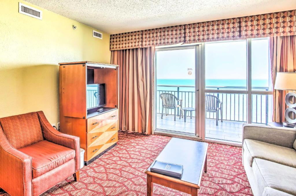 a living room with a couch and a television and a balcony at Beachfront Family Condo with View and Pool Access in Myrtle Beach