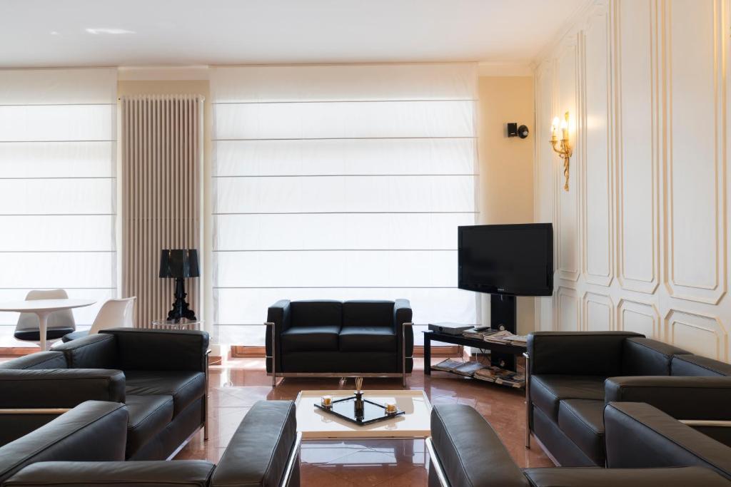 a living room with black leather furniture and a flat screen tv at Hotel Tourist in Turin