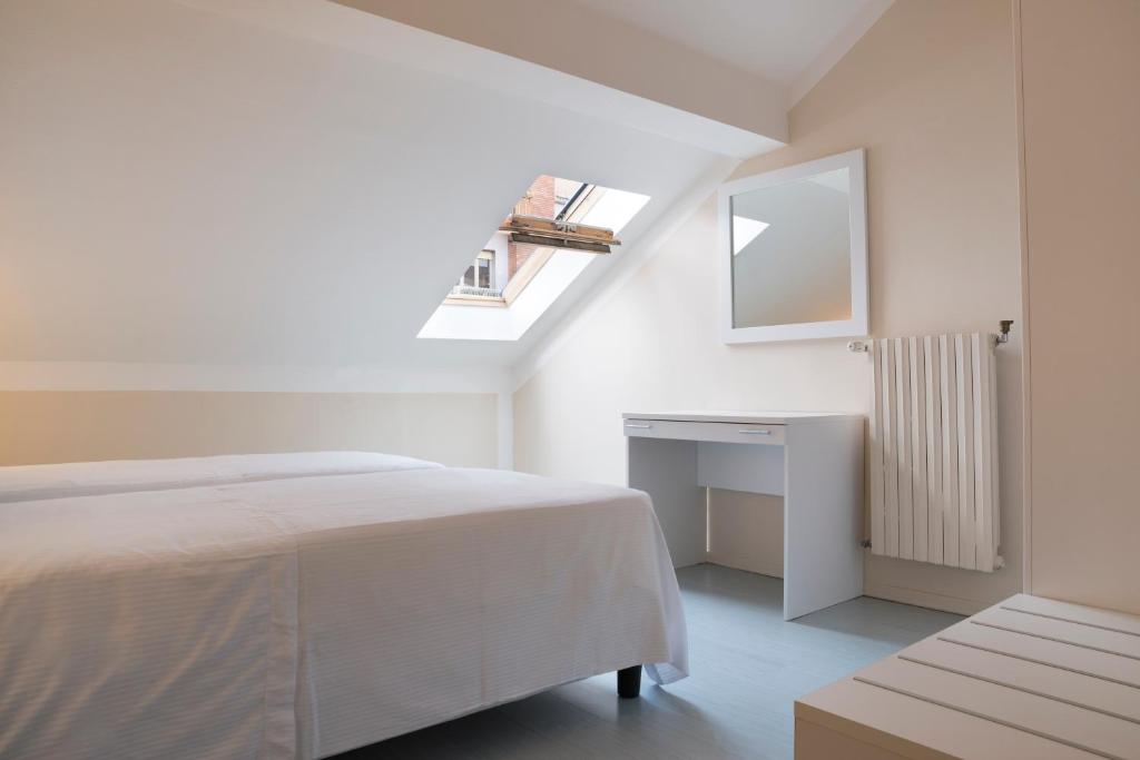 a white bedroom with a bed and a skylight at Hotel Tourist in Turin