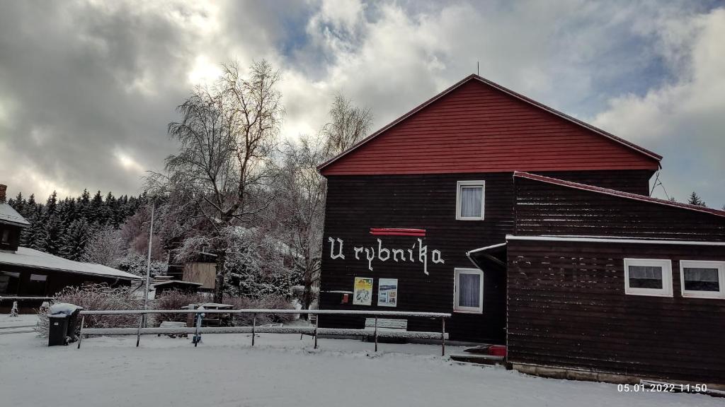 MariánskáにあるPenzion U Rybníkaの雪の上に看板を載せた建物