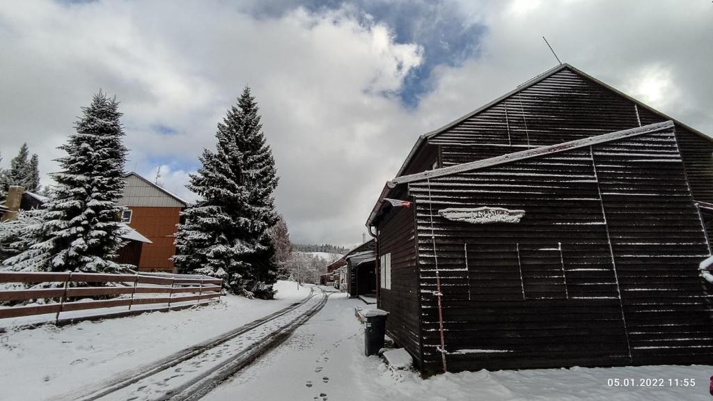 a barn is covered in snow next to some trees at Penzion apartmány Aninka in Mariánská