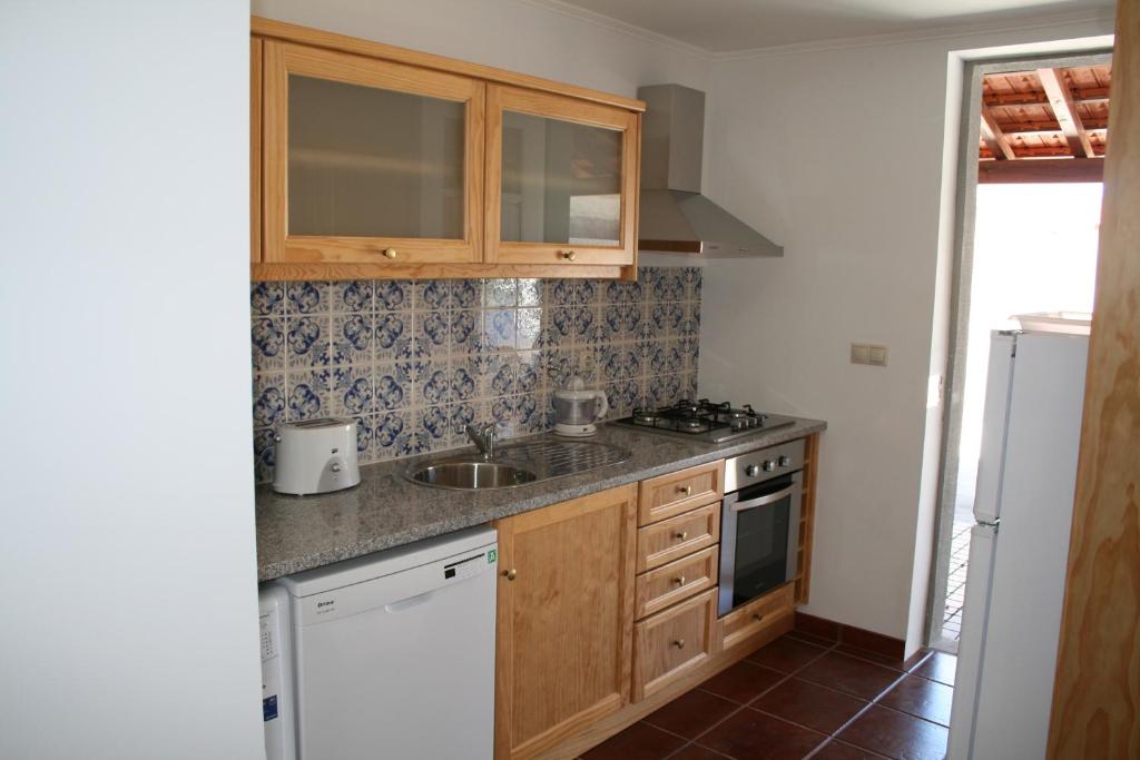 a kitchen with wooden cabinets and a sink at Murtosa House in Torreira