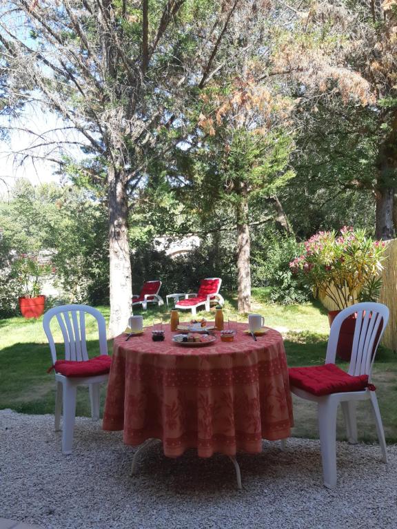 una mesa con un mantel rojo y dos sillas con velas en Suite avec jardin entre Aix en Provence, Luberon et Verdon, en Peyrolles-en-Provence
