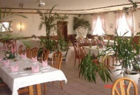 a dining room with tables and chairs and plants at Zeesener Gasthof in Königs Wusterhausen