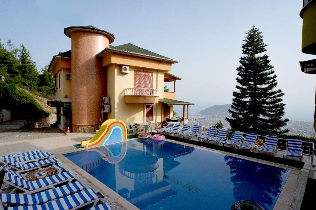 a swimming pool with chairs and a slide in front of a house at Berkay Villas 2 in Alanya