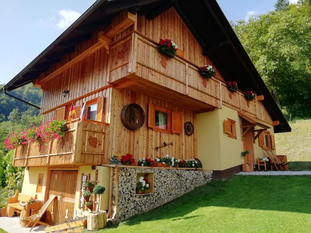 a house made out of wood with flowers on it at Počitniška hiška Kašta in Luče