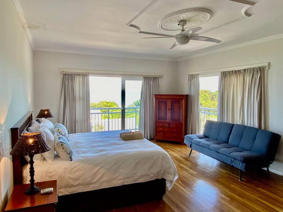 a bedroom with a bed and a blue couch at Beautiful beach house on Prince's Grant Estate in Blythedale