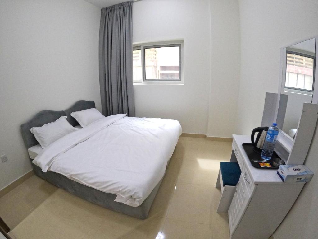 sypialnia z łóżkiem z białą pościelą i oknem w obiekcie Karama Star Residence (Home Stay) w Dubaju