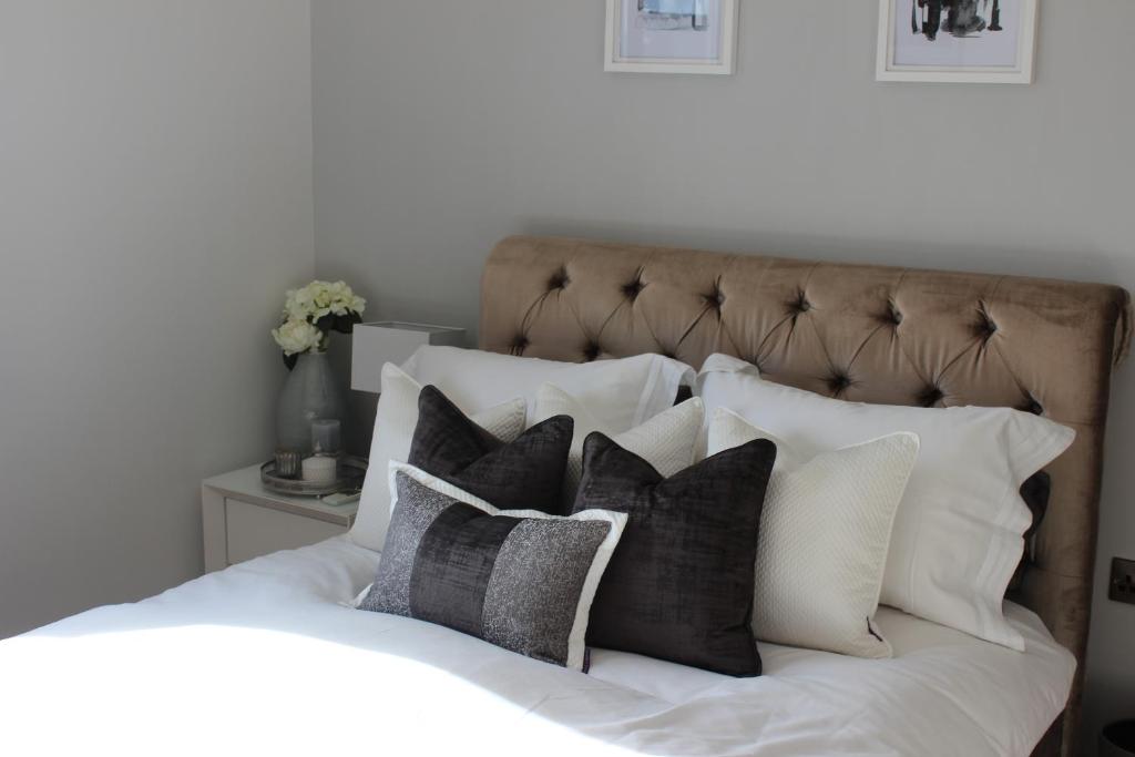 a white bed with black and white pillows at Seren Las, Tenby in Tenby