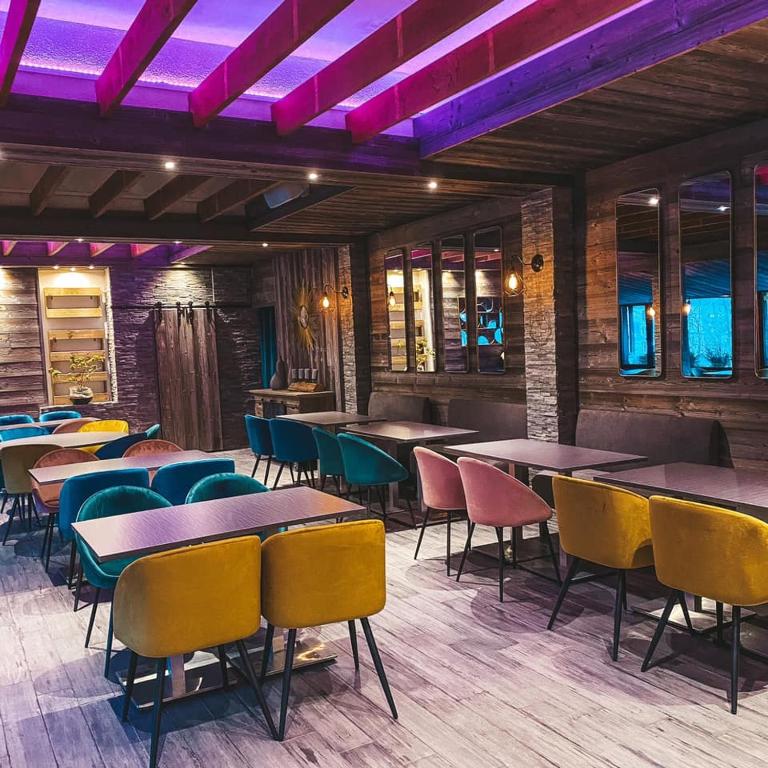 a restaurant with tables and chairs and purple lighting at Hotel Le Panorama in Le Mont-Dore