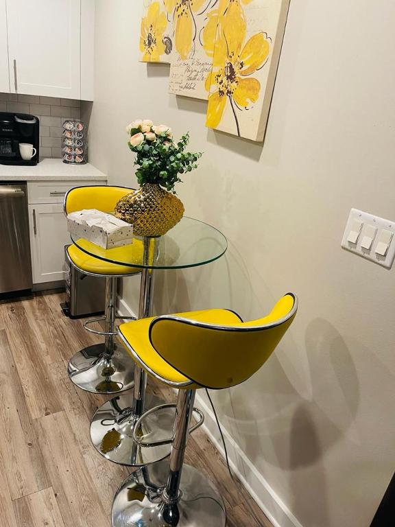 a kitchen with two yellow bar stools and a glass table at **Dream Luxury ** in the high rise downtown Orlando in Orlando
