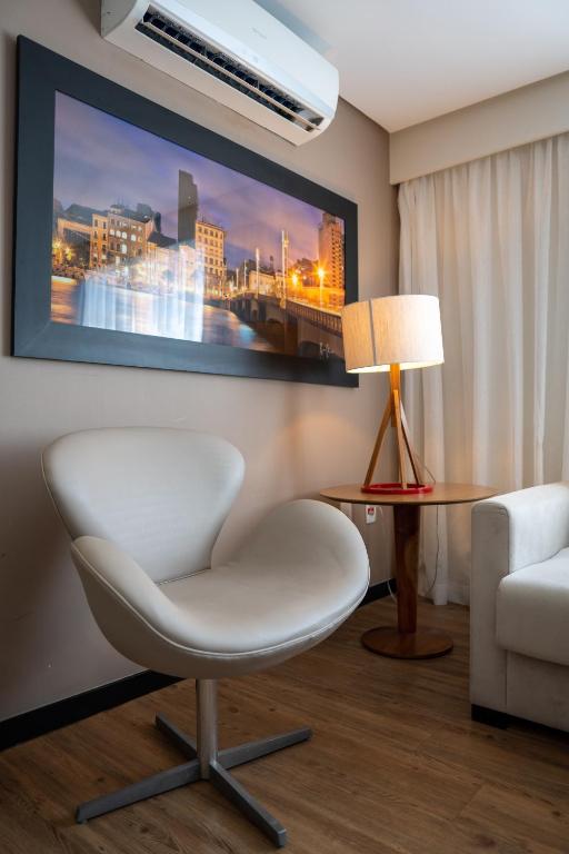 a living room with a white chair and a table at Roomo Praia de Boa Viagem Residencial in Recife