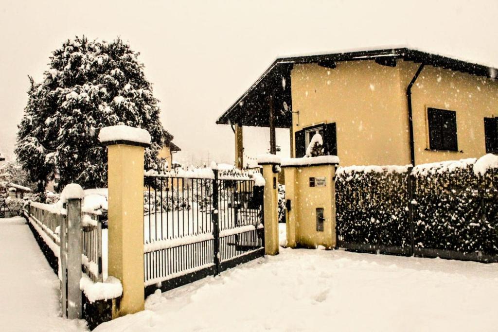 una valla cubierta de nieve frente a un edificio en villa verde bed and breakfast en Uggiate