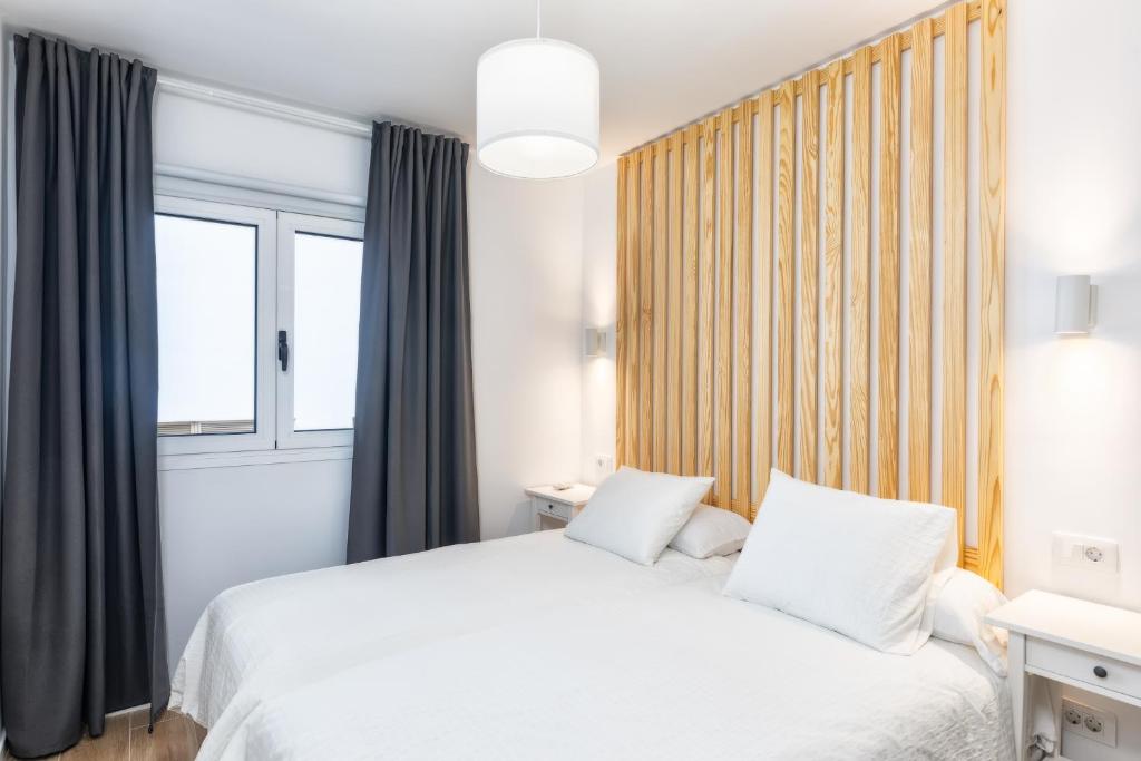 a bedroom with a white bed and a window at Duplex Tendal - Amplio y reformado adosado in Santa Cruz de la Palma