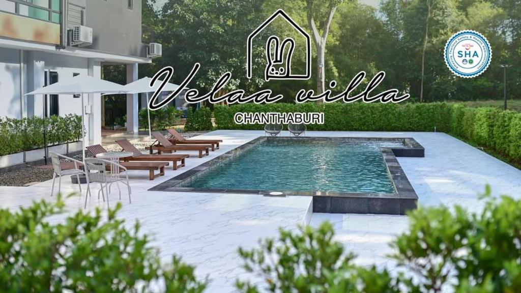 uma piscina com cadeiras, uma mesa e uma placa em Velaa pool villa em Ban Khung Kraben