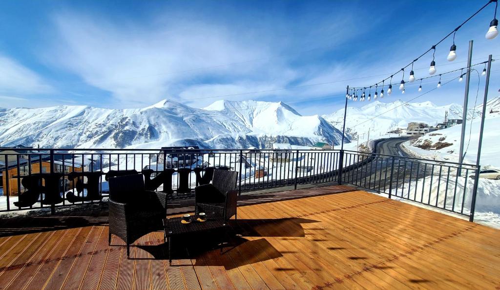 une table et des chaises sur une terrasse avec des montagnes enneigées dans l'établissement Gudauri Winter House, à Goudaouri