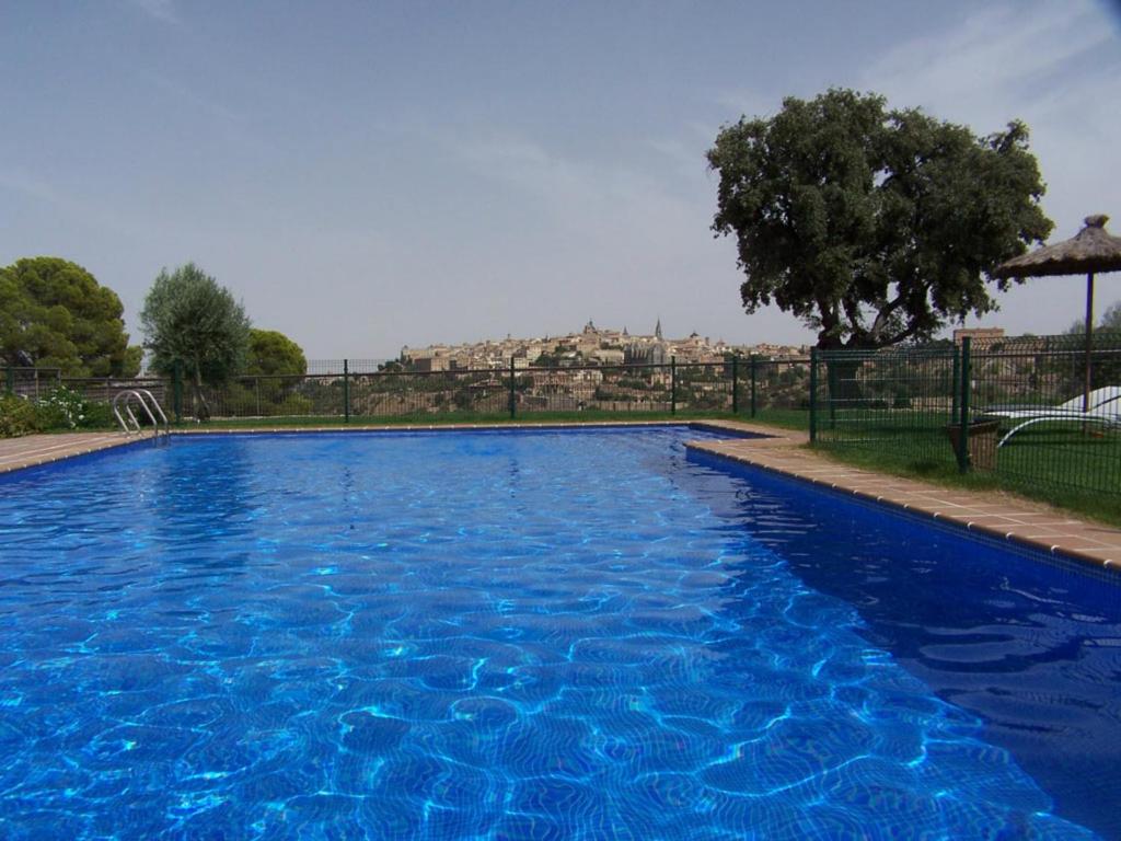 a large blue swimming pool with a building in the background at Hotel Cigarral el Bosque in Toledo