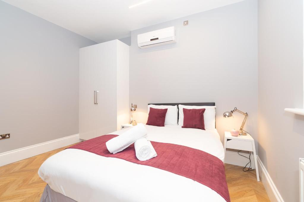 una camera da letto con un grande letto bianco con cuscini rossi di Stunning Hyde Park Apartments a Londra