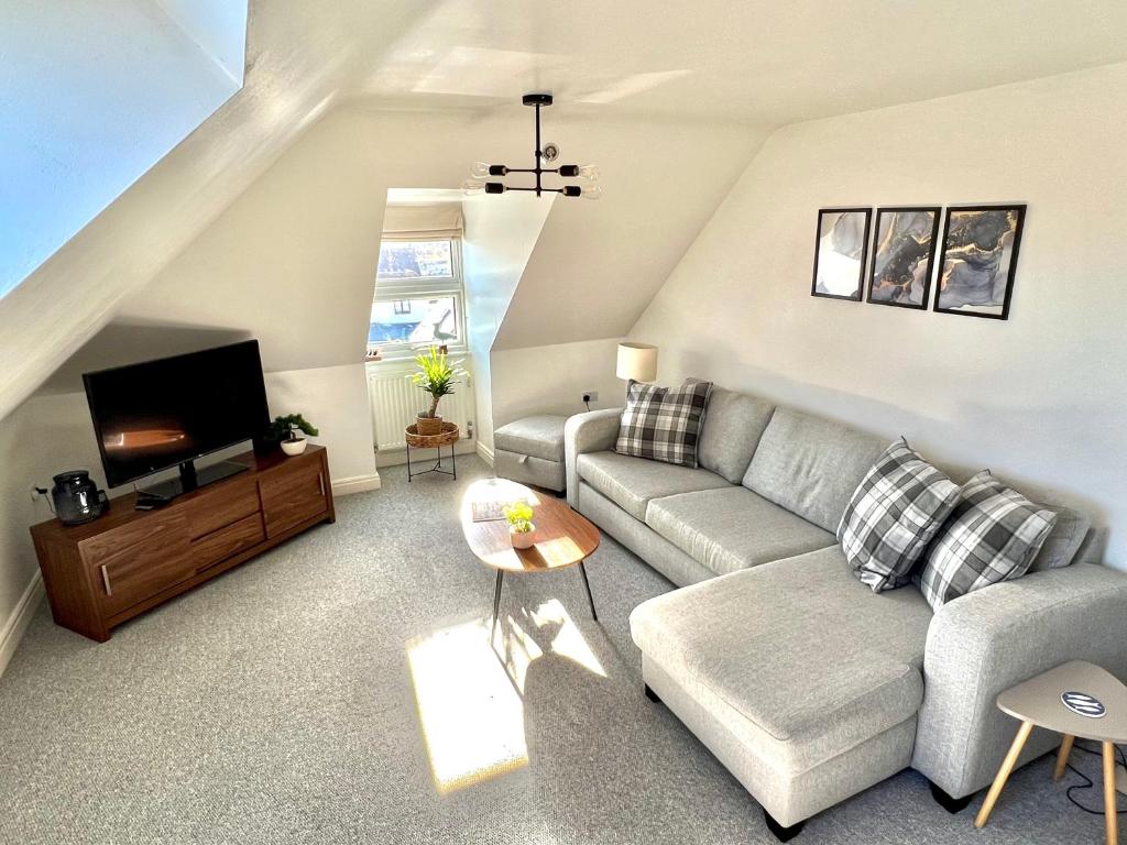 uma sala de estar com um sofá e uma televisão em Swanage Holiday Penthouse Apartment, Moments from Beach and Town, On Site Parking, Fast WIFI, Sleeps up to 6, Rated Exceptional em Swanage