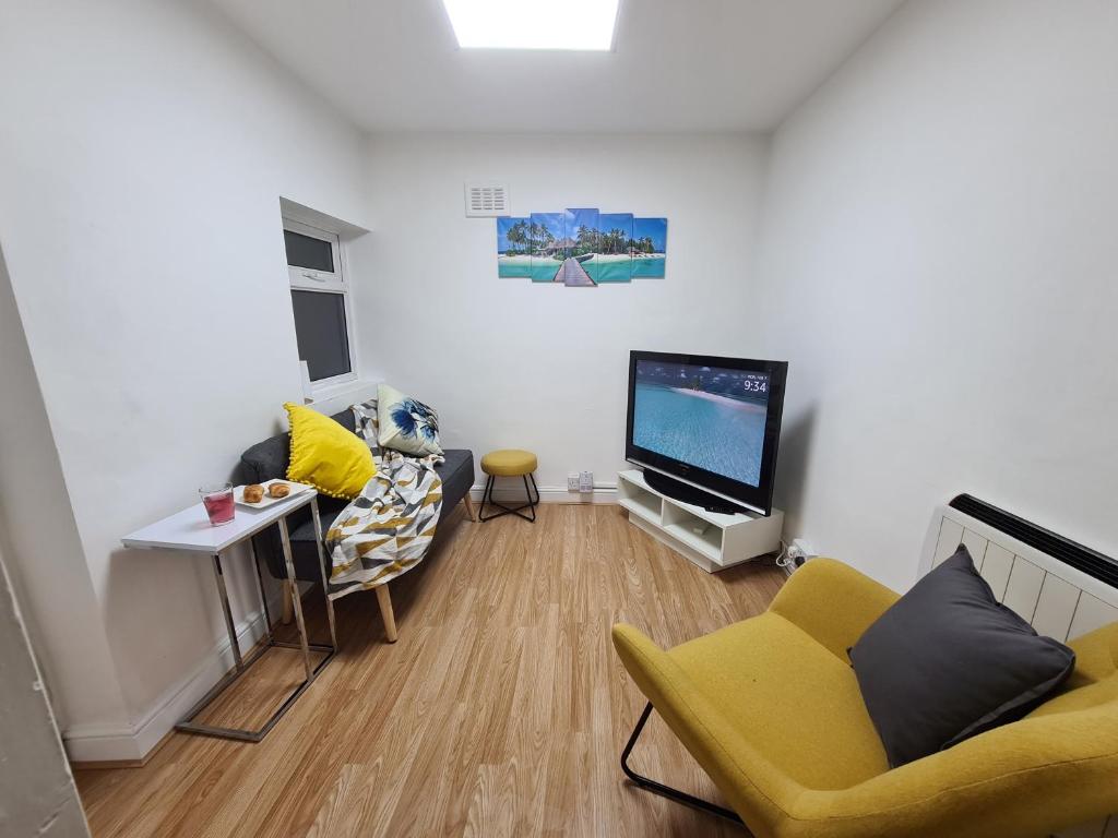 a living room with a yellow chair and a flat screen tv at Property Malak Homz - West Street 2 Bed Premium Apartment in Leicester