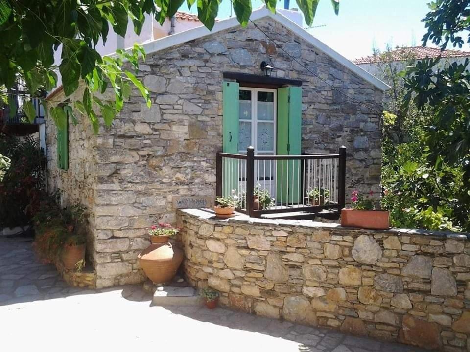 une maison en pierre avec une porte verte et un mur en pierre dans l'établissement Villa Panayiota, à vieille ville d'Alonissos