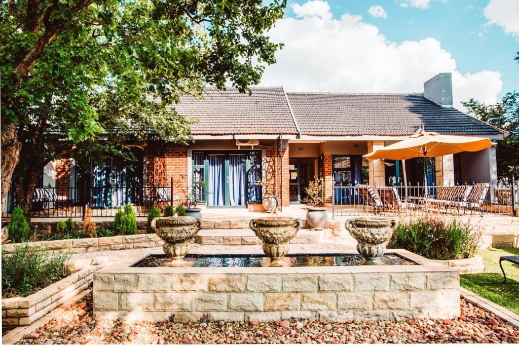 ein Haus mit einem Brunnen vor einem Haus in der Unterkunft Le Grant Guesthhouse in Kroonstad