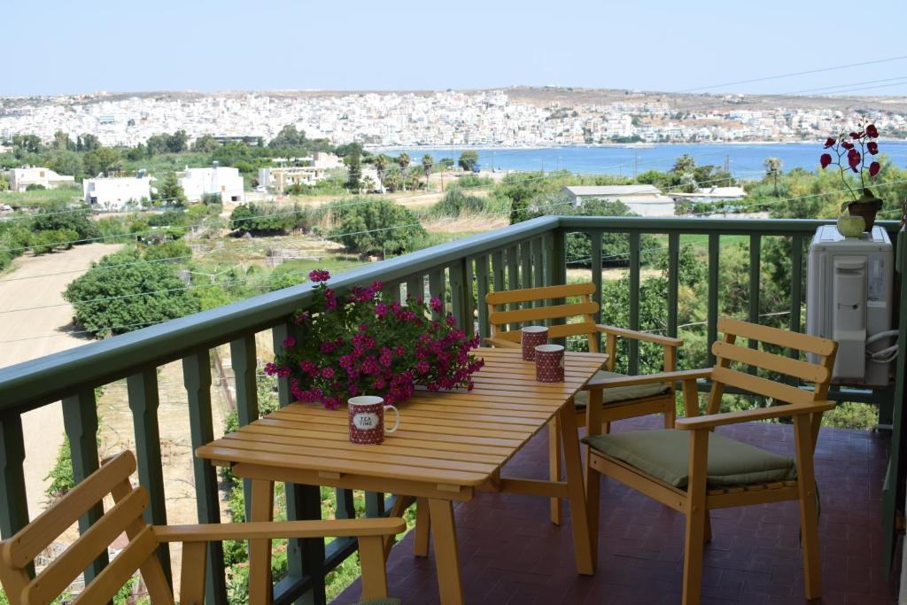 a wooden table with chairs and flowers on a balcony at Bellevue Apartments in Sitia