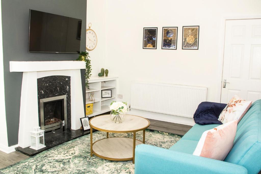 a living room with a blue couch and a fireplace at Trafford House - Stylish 3-bed home with private parking in Manchester