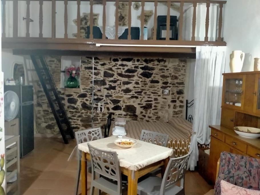einen Tisch und Stühle in einer Küche mit einer Steinmauer in der Unterkunft La lammia di Pisticci in Pisticci