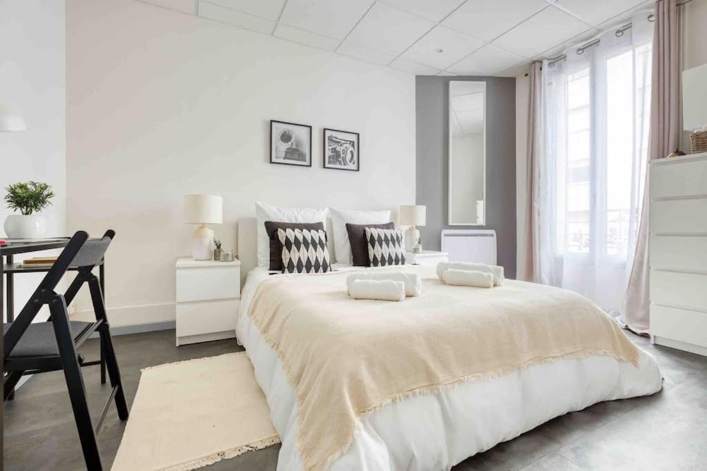 - une chambre blanche avec un grand lit et un bureau dans l'établissement Ô Paisible proche Paris Wifi Netflix Parking, à Saint-Ouen