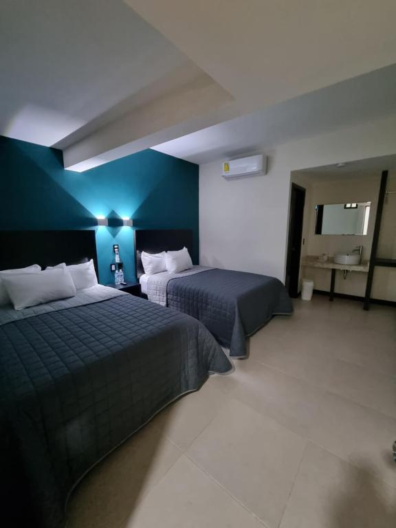 ein Schlafzimmer mit 2 Betten und einer blauen Wand in der Unterkunft EMS Hoteles Centro Histórico in Veracruz